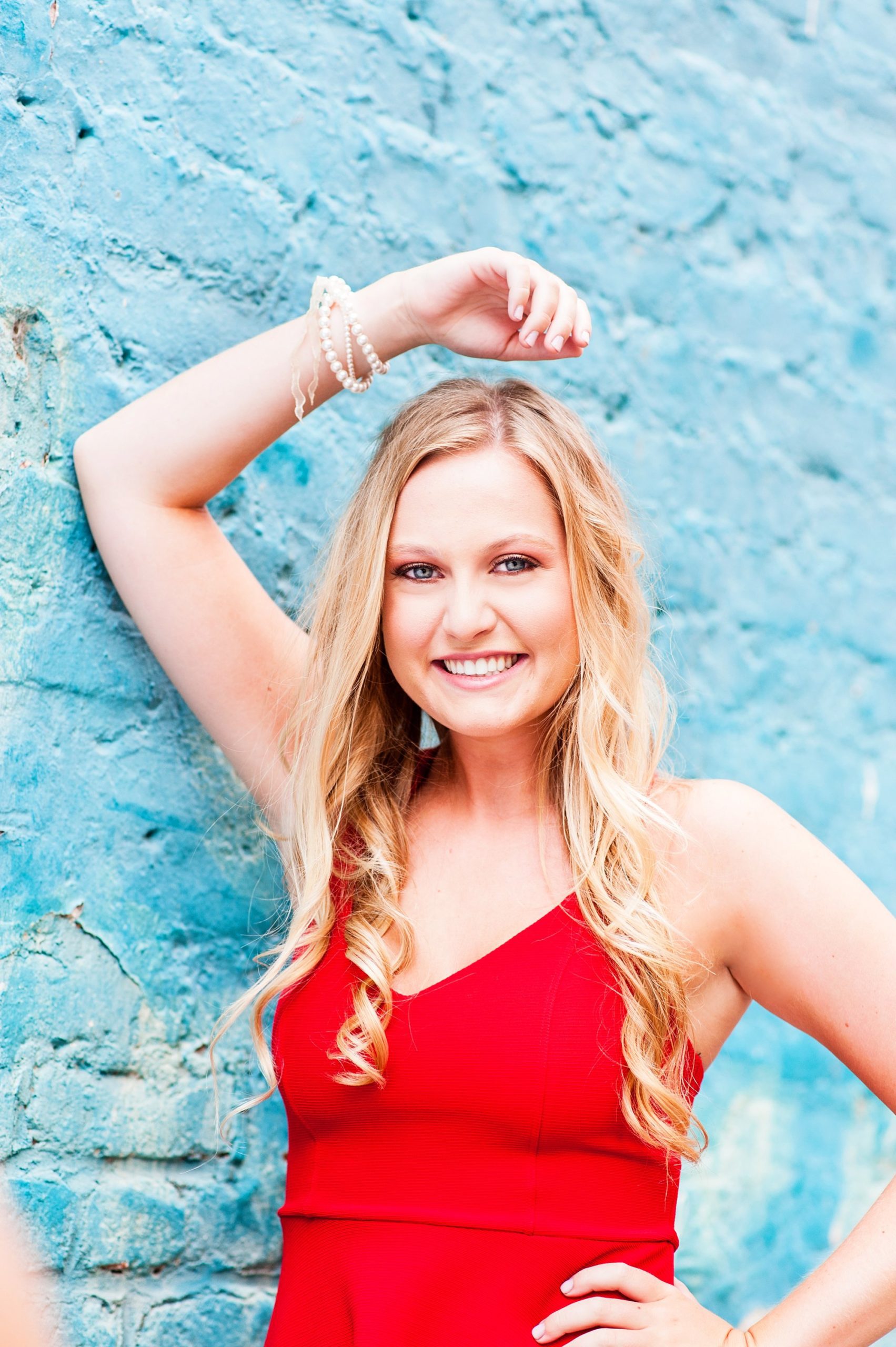 high school senior girl wearing red dress against teal blue brick wall shockoe bottom richmond virginia