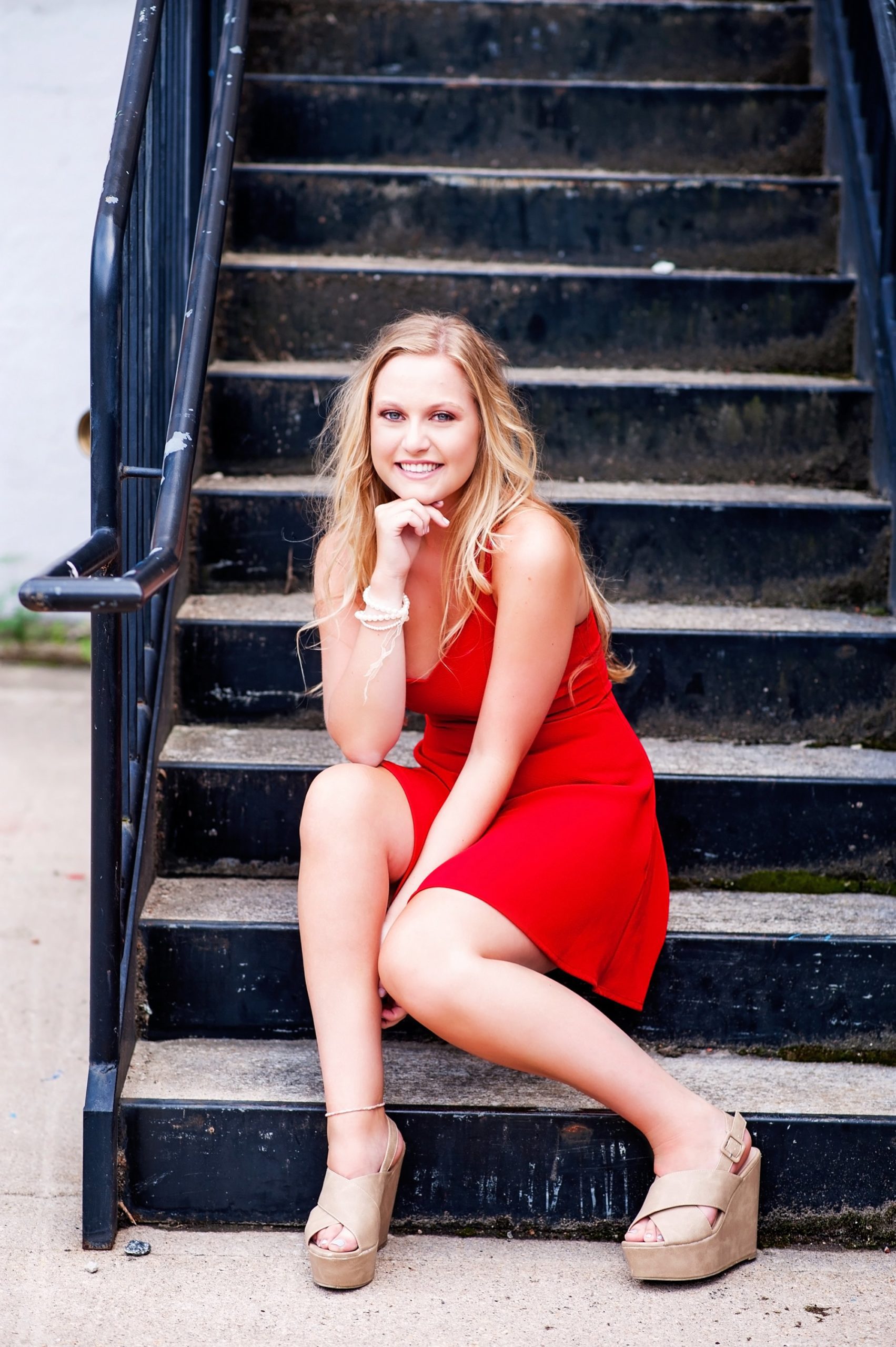 high school senior girl in red dress sitting on staircase downtown richmond va