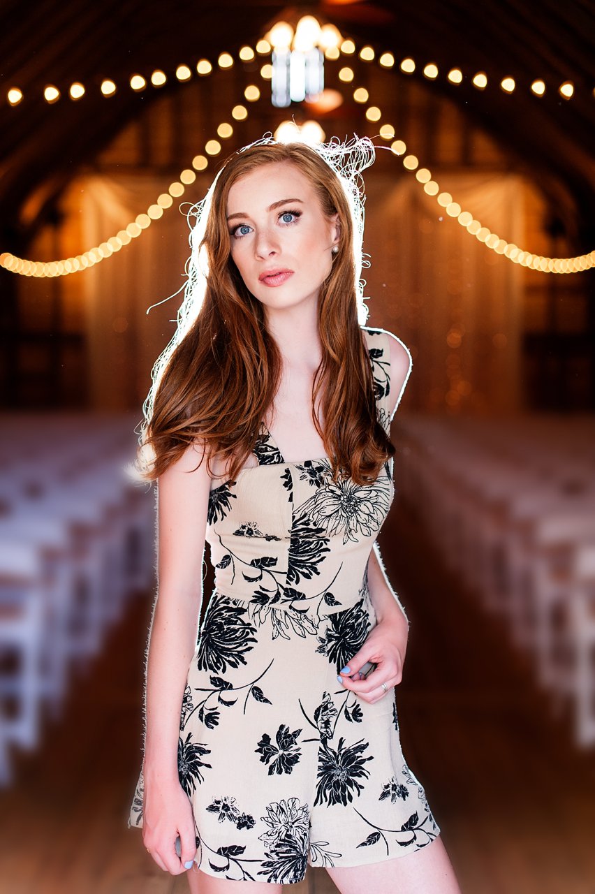 high school senior portraits with red head in barn with backlight