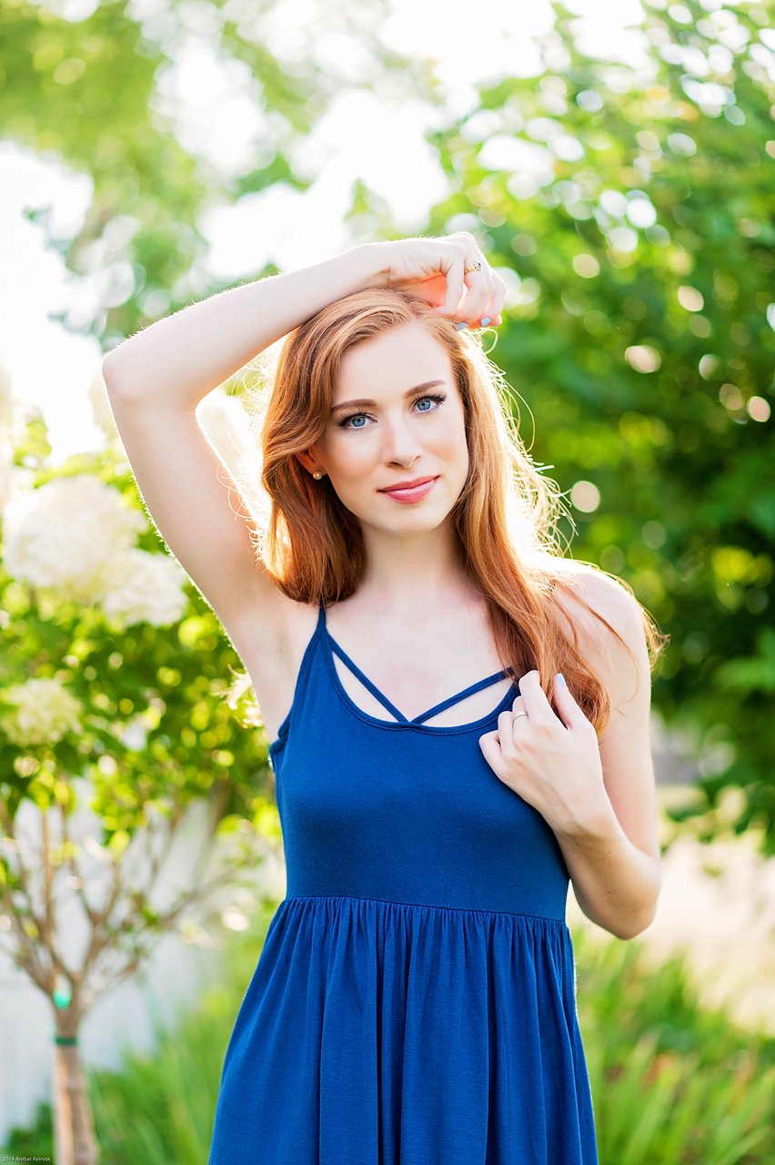 red head senior wearing blue dress with backlight